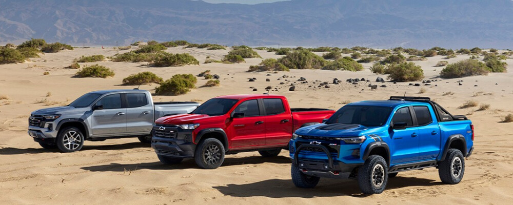 Three 2024 Chevrolet Colorado trucks lined up, showcasing the off-road-ready Z71, the adventurous Trail Boss, and the extreme ZR2 trims