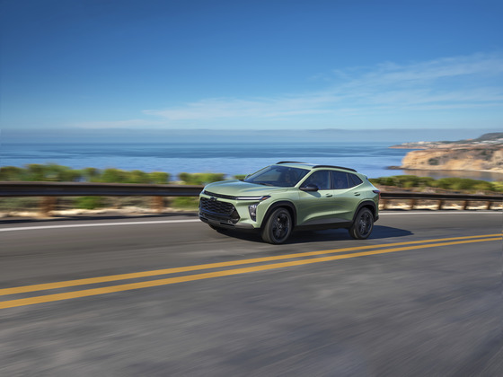 A vibrant 2025 Chevrolet Trax Activ in Cactus Green cruising along a scenic coastal highway, showcasing its adventurous spirit and stylish design