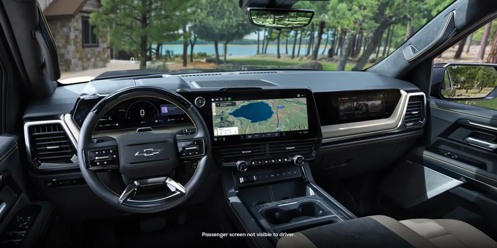Photo of the driver cockpit in the 2027 Chevrolet Silverado including driver information display behind the steering wheel, larger infotainment system with google maps on it, and a passenger screen displaying YouTube.